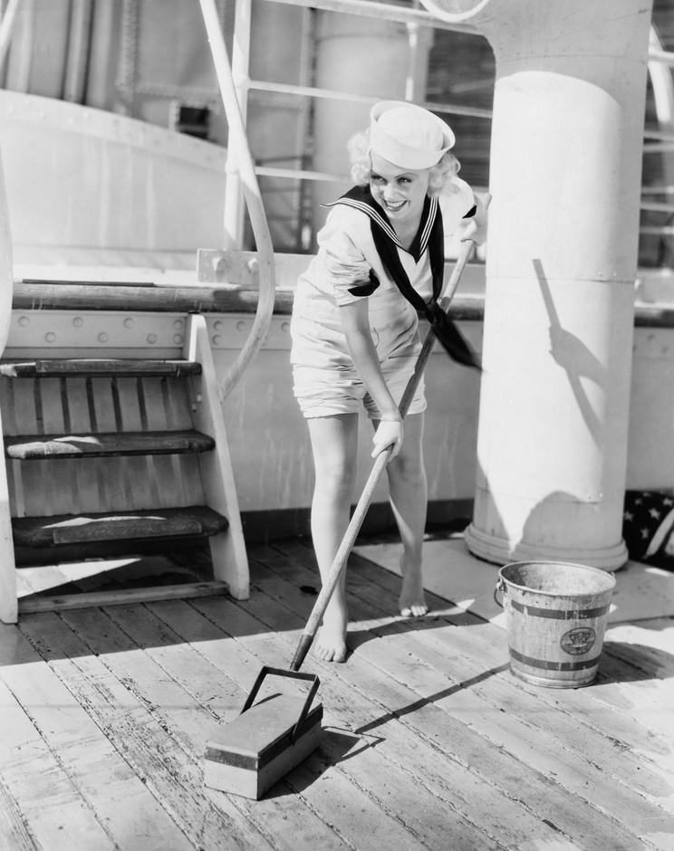 Female sailor swabbing boat deck